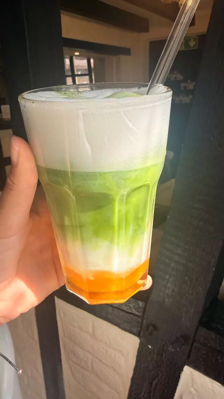 Iced Matcha Latte mit Fruchtsirup im hohen Glas