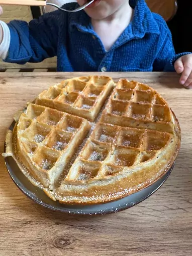 Kind isst hausgemachte Waffel mit Puderzucker