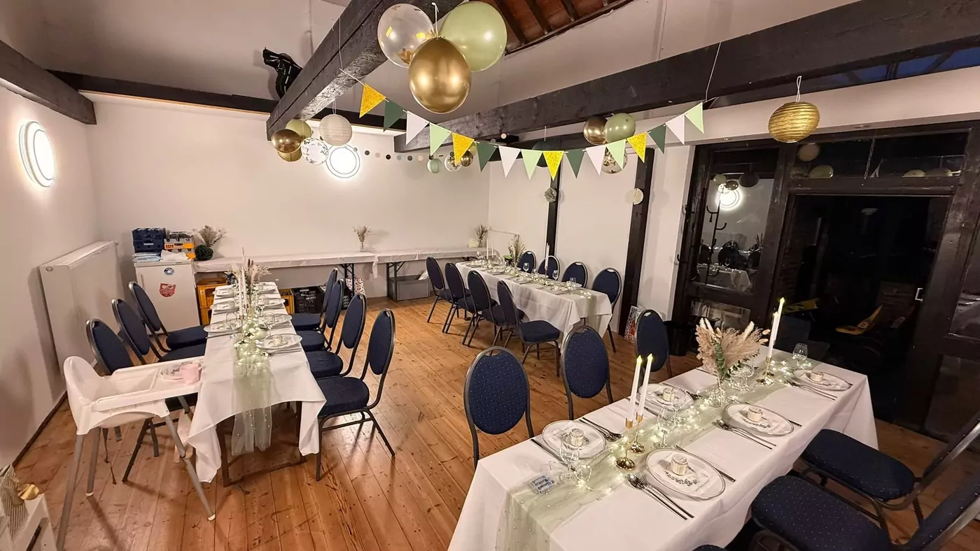 Eventscheune mit goldenen Ballons, gedeckten Tischen und Holzbalken-Decke