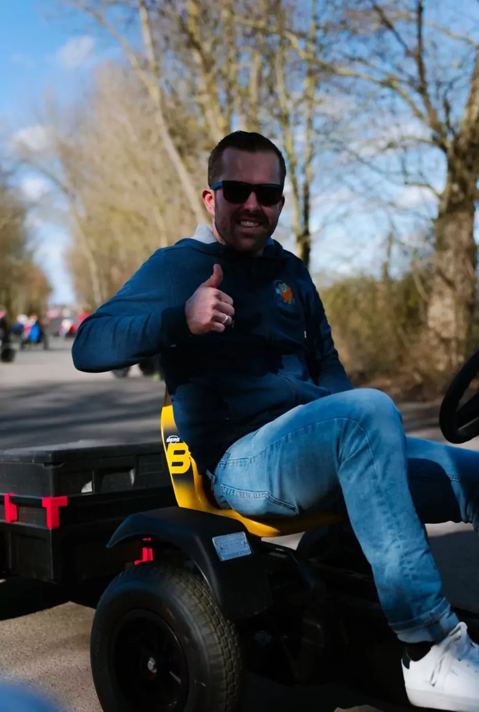 Thomas mit Daumen hoch auf einem Kettcar vor dem WuselWerk