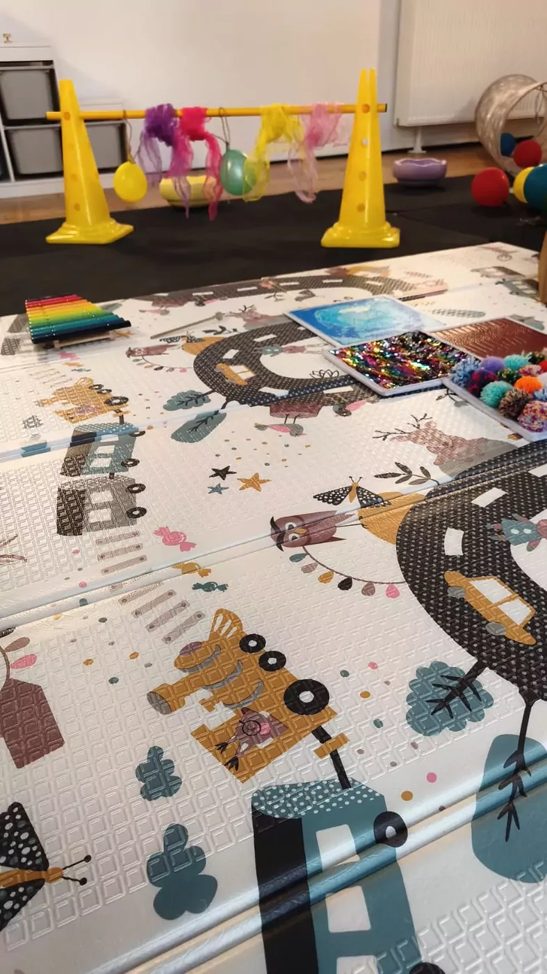 Bastelmaterial und Klangstäbe auf einer Spielmatte im Kursraum