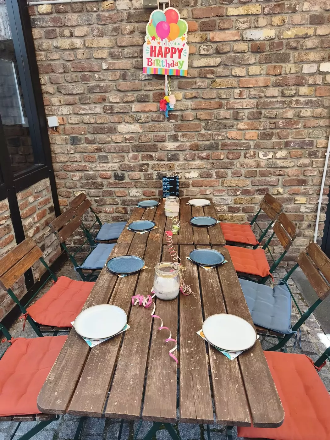 Festlich gedeckte Geburtstagstafel mit Happy-Birthday-Girlande im Innenhof